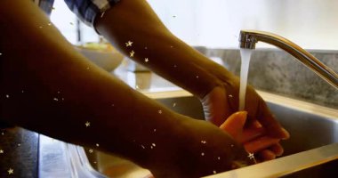 Ev aşçısının musluğu çevirmesi ve yıldız şeklinde kaplamalarla mutfak sağlığı için ellerini yıkaması. Temizlik, hijyen, sağlık, evcil, minimalist, ferahlatıcı, sağlık