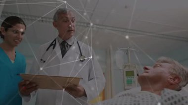 Kıdemli doktor hasta notlarını okuyor ve hastane pompasının yanında kırmızı kalemle yazı yazıyor. Sağlık ekibi, sağlık hizmetleri, klinik, işbirliği, profesyonellik, hasta bakımı, teşhis