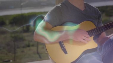 Güvertede gitar çalan bir adam sürüklenen ışık dalgalarını başlatıyor ve duygusal bir müzik söylüyor. Müzisyen, akustik, melodi, açık hava, dingin, sanatsal, yaratıcı