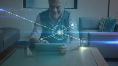 Yaşlılar tableti tıklayarak teknoloji ağını etkinleştiriyor. Oturma odasında veri düğümlerini görselleştiriyor. Teknoloji, bağlantı, yenilik, fütürizm, dijital, modern, zeki