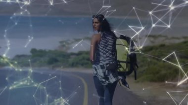 Sahil yolunda yürüyen yalnız bir kadın teknolojiyi etkinleştiriyor harita bağlantısı için tarama yapıyor. Macera, keşif, teknoloji, bağlantı, açık hava, minimalizm, yolculuk