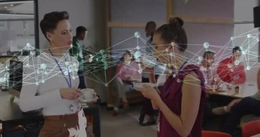 İki kadın şebeke salonunda ellerinde akıllı telefonlar tutarak titreşimli şebeke hatlarını gösteriyor. İşbirliği, profesyonel, iletişim, dijital, kentsel, gösterişli, katılım