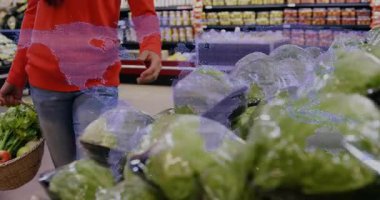 Market koridoruna giriyoruz, sepet toplayan bir kadın marul topluyor ve tazeliği inceliyor. Tazelik, süpermarket, organik, sağlıklı, aşçı, tüketici, doğal