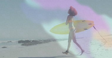 Kumlu sahilde sarı sörf tahtası taşıyan yürüyen bir kadın. Bileğinde tasma olan turuncu bir bikini. Kopya alanı. Sahil, sahil, yaşam tarzı, minimalizm, rahatlama, açık hava, macera