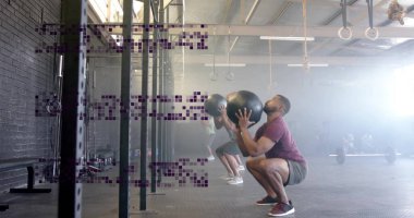 Göğüs seviyesinde tıp toplarını tutan stajyerler endüstriyel spor salonunda antrenman yapıyorlar. Spor, güç, eğitim, egzersiz, dayanıklılık, egzersiz, endüstriyel