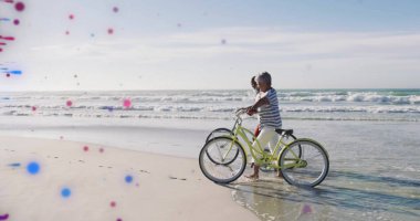 Yürüyen olgun bir çift okyanus kıyısı boyunca bisiklet sürüyor. Dalgalar yumuşak, kopyalama alanı var. Macera, eğlence, sağlık, açık hava, sükunet, aktivite, arkadaşlık.
