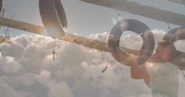 Antrenman kıyafeti giyen tırmanan sporcu engelli parkurunda zincire vuruyor, kopyalama alanı kullanıyor. Macera, fitness, dayanıklılık, açık hava, spor, güç, mücadele