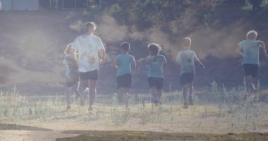 Koşu koçu ve stajyerler tozlu atletizm tişörtleri giyip kuru çim tarlasında spor peşinde koşuyorlar. Spor, takım çalışması, açık hava, atletik, aktivite, gençlik, enerji