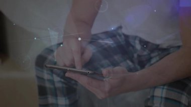 Yetişkin bir adam kanepeye dokunarak objektifle görüntü alabilmek için teknik veri hatları oluşturuyor. Teknoloji, bağlantı, dijital, yenilik, eğlence, ev ofisi, modern