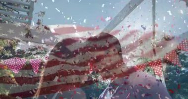 Alnını fırçalayan, terasta öpüşen, bayrak altında kıvrımlı konfeti kıvılcımları çıkaran bir çift. Romantizm, kutlama, vatanseverlik, neşe, açık hava, şenlik, samimiyet