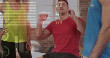 Jimnastik salonunda yumruk kaldıran antrenör harita turtası ve bar çizelgeleriyle ilerlemeyi açıklıyor. Eğitim, fitness, veri görselleştirme, ilerleme, koçluk, sağlık, motivasyon