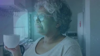 Mutfakta kıdemli bir kadın fincanı kaldırıyor, içkisini yudumluyor ve yüzen sağlık parçacıklarıyla dışarı bakıyor. Meditasyon, dinginlik, sükunet, tefekkür, doğadan esinlenilmiş, sağIık, gündelik