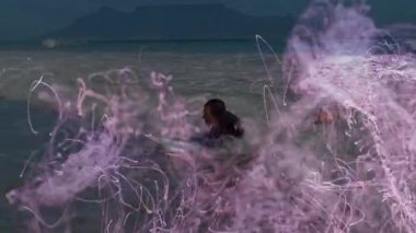 Erkek sörfçü çözünmeden önce teknoloji demosunda mor spiral kıvılcımlar saçıyor. Sörfçü, okyanus, dalga, ışıltı, enerji, su, doğa