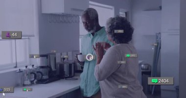 Üst düzey kadın mutfakta partneriyle kahvesini yudumluyor pazarlama ikonlarını sürüp artan ölçüler gösteriyor. El bilgisayarı, yerli, rahat, dijital, etkileşim, rahatlama, çağdaş