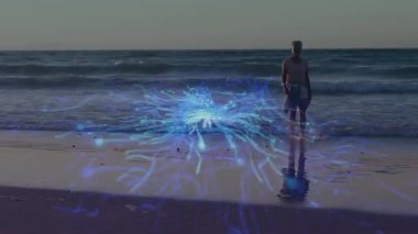Kıdemli bir kadın kumsala adım atıyor ve teknoloji gösterisi için kıyı boyunca sürünen parlak mavi ağı aktifleştiriyor. Işık, sükunet, yenilik, kıyı, dijital, dinginlik, dinginlik