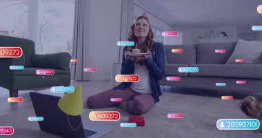 Evde elinde kek tabağı tutan kızıl saçlı bir kadın, dizüstü bilgisayarı, parti şapkası, köpeği, yüzen ikonları var. Canlı, modern, rahat, dijital, kutlama, yaşam tarzı, rahatlama