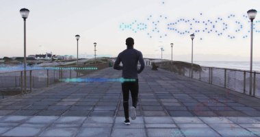 Atletik bluz ve tayt giymiş koşan bir adam şafak vakti rıhtım boyunca sokak lambası direkleri ile dolaşır. Fitness, egzersiz, manzara, açık hava, aktivite, canlılık, sağlık