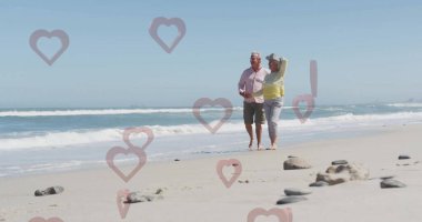 Sahilde çıplak ayakla yürüyen kıdemli bir çift. Geniş kenarlı güneş şapkaları ve kayaları var. Kopya alanı. Sakin, sakin, ufuk çizgisi, dinginlik, açık hava, doğal, arkadaşlık