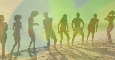 Sekiz yetişkin mayo giyiyor, dizlerini eğiyor ve kumlu sahilde kollarını kaldırıyor. Gün batımı, zindelik, zindelik, birlik, eğlence, açık hava, enerjik