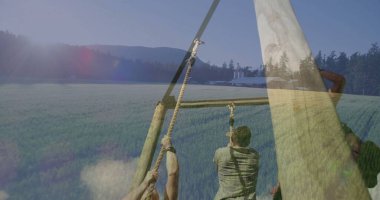 Yeşil alanda tırmanma engeli, eldivenler ve kayışlar, kalın ipler, ahır siloları. Macera, takım çalışması, dayanıklılık, açık hava fitness, kırsal alan, meydan okuma, fiziksel aktivite