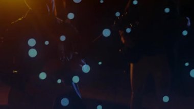 İki grup arkadaşı enstrümanları akort ediyor ve sıcak sahne ışığı altında tıngırdayan ritim, sürüklenen mavi kabarcıklar. Müzisyenler, performans, ortam, minimalist, sanatsal, akustik, yaratıcı