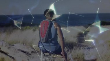 Okyanusa bakan kayalarda oturan bir adam ağ çizgileri oluşturarak teknolojik bağlantıyı resmediyor. Teknoloji, yenilik, bağlantı, fütüristik, dijital, veri, iletişim