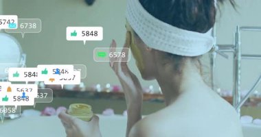 Yanağa cilt maskesi takan bir kadın, tepki simgeleri çember çizerken nişan büyümesini gösteriyor. Cilt bakımı, rahatlama, sağlık, güzellik, bencillik, sükunet, hijyen.