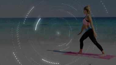 Pembe hasırlı plajda hafif hamleler yapan bir kadın girdap gibi dönen bir dizilimle sağlığını arttırıyor. Zindelik, sağlık, farkındalık, dinginlik, güç, açık hava, meditasyon