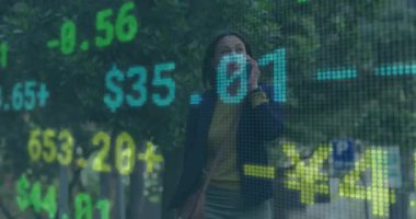 Yetişkin bir kadın kaldırıma çıkıyor, telefon görüşmesi yapıyor ve hareketli finans rakamlarını takip ediyor. İş, finans, kentsel, teknoloji, profesyonel, pazar, dijital