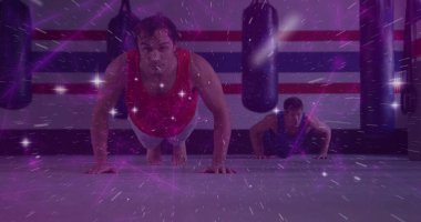 Dövüş sanatları salonunda iki atletik adam, ağır kum torbaları ve mor ışık. Güç, zindelik, antrenman, spor, kararlılık, canlılık, enerji