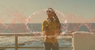 Korkuluklara yaslanmış, hardal gömlekli bir kadın gezinti alanında akıllı telefon tutuyor, kulaklık takıyor. Manzara, gelişigüzel, modern, teknoloji, doğa, rahatlık, refah