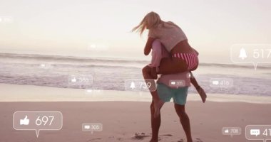 Kadın partnerinin sırtına atlıyor, gün batımında plajda sosyal medya alarmları artarak sırtına biniyor. Romantik, boş zaman, sükunet, bağlantı, açık hava, yaşam tarzı, kutlama