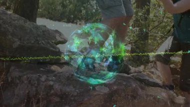 Kıdemli yürüyüşçüler, cihazı verdikten sonra ormanda kayalara tırmanıyor ve holografik dünya teknolojisini izliyorlar. Macera, keşif, teknoloji, doğa, takım çalışması, açık hava, keşif