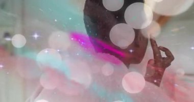 Elini kulağına doğru kaldırdığında, bir kadın aynada aynaya doğru ışık efektleriyle küpe takıyor. Yansıma, tımar, zarafet, dinginlik, cilt bakımı, kibir, bencillik.