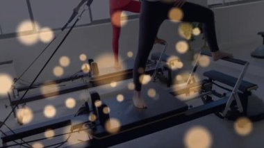 Reformist pilatesine giren iki kadın çekirdek nişanı gösteren animasyon gerilimli kabloları çekiyor. Zindelik, güç, esneklik, sağlık, denge, egzersiz, sağlık