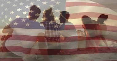 Dostlar gün batımında sahile gelirler ve çizgili battaniyeye kurulup parlayan ufku gösterirler. Deniz kenarı, yoldaşlık, rahatlama, manzara, sıcaklık, rahatlık, siluet.