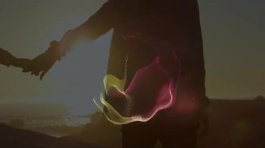 Gün batımında sahilde dans eden çift el ele tutuşarak neon dijital ağ teknolojisinin etkisinin genişlemesine neden oluyor. Romantik, siluetler, enerjik, canlı, sanatsal, geleceksel, bağlantı