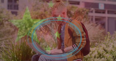 Şehir avlusunun merdivenlerinde dizüstü bilgisayarda çalışan öğrenci sırt çantalı bombardıman ceketi giyiyor. Üretkenlik, yenilik, modernlik, eğlence, girişimcilik, bağlantı, profesyonel