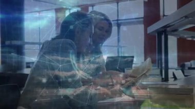 Kadınlar referans kitabını açıp bilgisayara erişirken dijital rehberlik teknolojisi araştırmalarını üstüste koyuyor. İşbirliği, takım çalışması, yenilik, modern, profesyonel, dijital, öğrenim