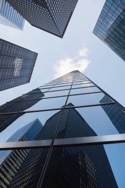 Düz dizayn, açık mavi gökyüzünün altında yansıtıcı gökdelenler oluşturan kanyon efektlerini gösteriyor. Modern, kentsel, mimari, geometrik, fütürist, profesyonel, kurumsal