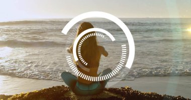 Turkuaz taytlı meditasyon yapan kadın deniz yosunlarının üzerinde oturuyor. Dijital kaplamayla okyanusa bakıyor. Meditasyon, sağlık, dinginlik, farkındalık, sahil, doğa, dijital arayüz