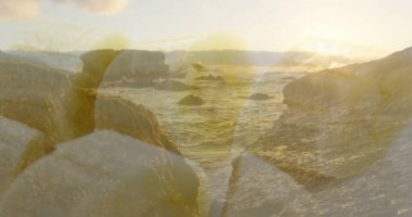 Kıyı şeridinde, ufukta güneş ışığı altında yüzen kayalıklar ve dalgalar. Kıyı şeridi, deniz manzarası, açık hava, sükunet, doğal gün batımı.