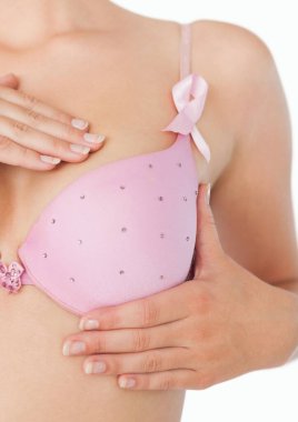 Göğüs kanseri olan sütyenli bir kadının beyaz arka plana karşı farkındalık kurdelesi.