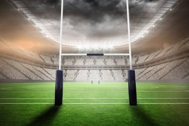 Stadyumun kıvrımlı çatısının altında çim tarlası ve projektörleri olan bir çift dik kale direği. Stadyum, spor, arena, yarışma, mimari, gece, açık hava