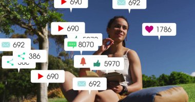 Park Hill 'de oturan kadın mavi yastıklı, akıllı seğiren ve bilgilendirme baloncuklarıyla açık kitap okuyor. Açık hava, rahatlama, farkındalık, dijital, çağdaş, boş zaman, doğa