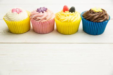 Düz dizaynlı, kremalı ve şekerli dört top kek beyaz masa üstünde oturuyor. Lezzetli, şekerleme, pasta, tatlı, estetik, renkli, kutlama