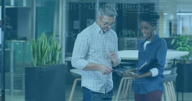 Dijital verileri tartışan iki profesyonel açık ofiste tablet ekranı işaret ediyor, klasörle. İşbirliği, takım çalışması, yenilik, modernlik, profesyonellik, üretkenlik, şirket