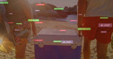 Yüzme şortlu adamlar kumlu plajda mavi-beyaz soğutucuyu kuşatıyorlar. Medya da üstlerinde. Yaz zamanı, dostluk, açık hava, eğlence, canlı, kıyı, macera