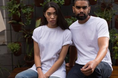 Beyaz tişörtlü çift oturuyor.