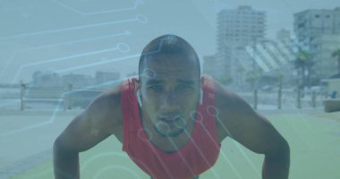 Yeşil paspas ve kulaklıklarla deniz kenarında kırmızı atletik bluz giyen yetişkin adam şınav çekiyor. Fitness, spor, sağlık, açık hava, motivasyon, aktif, manzara